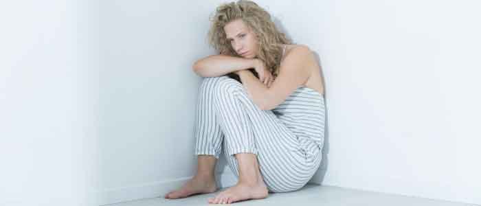 a young woman curled up into a corner looking depressed